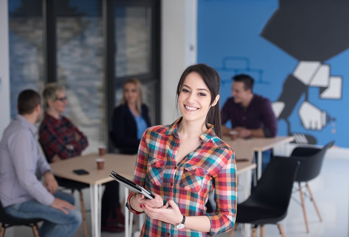 portrait of young business woman at office with team in backgrou portrait of young business woman at modern startup office interior, team in meeting in background